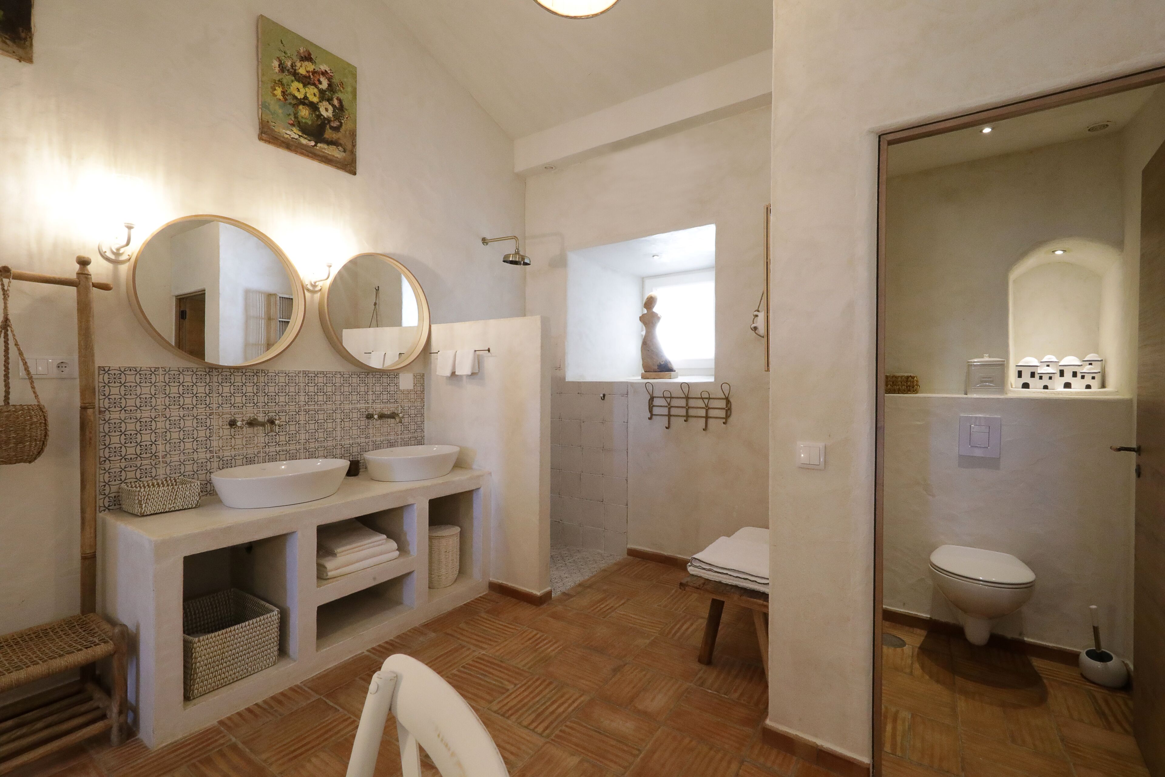 A bathroom with two sinks, a mirror, a shower, and a toilet.