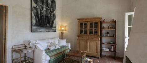 A living room with a white sofa, a wooden cabinet, a patterned rug, and a wall-mounted lamp.