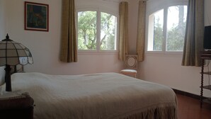 Een slaapkamer met een groot bed, een stoel, een tafel en een schilderij aan de muur.