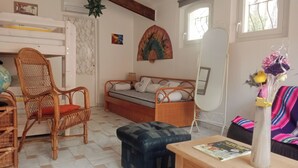 Een gezellige kamer met een bed, een stoel, een klein tafeltje en een spiegel.
