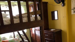 A bunk bed with floral bedding, a wooden dresser, a wall-mounted fan, and a small trash bin. - Family Friendly 2-bedroom Apartment in Vieux Fort (Vieux Fort)