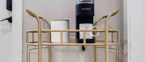 A bunk bed with a metal frame, a black heater on the wall, and a small table with a bottle and a decorative item.