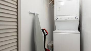 A laundry room with a washing machine and dryer, a towel rack, and a broom.