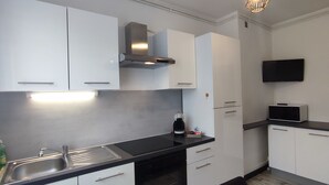 A modern kitchen with white cabinets, a black countertop, a stainless steel sink, a microwave, and a built-in stove.