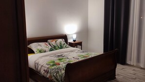 A bedroom with a bed, a nightstand, a lamp, and a window with curtains.