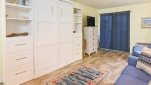 Een kamer met een grote witte garderobe, een blauwe bank en een kamerkleed met dessin.