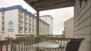 Een balkon met een tafel en stoelen, met uitzicht op een gebouw met een blauw-witte gevel.