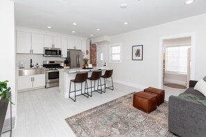 A modern kitchen with white cabinets, stainless steel appliances, and a central island with bar stools.