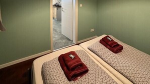 A room with two beds, a TV mounted on the wall, and a door leading to a bathroom. - Relaxen im Weindorf Mayschoß Fewo 1 (Mayschoß)