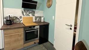 A compact kitchen with a wooden countertop, a built-in oven, and a black range hood. - Relaxen im Weindorf Mayschoß Fewo 1 (Mayschoß)