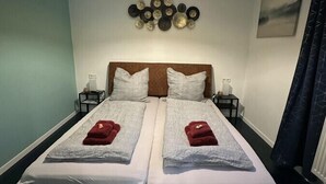 A double bed with two pillows, a bedside table, a wall-mounted light fixture, and a decorative wall piece. - Relaxen im Weindorf Mayschoß Fewo 3 (Mayschoß)