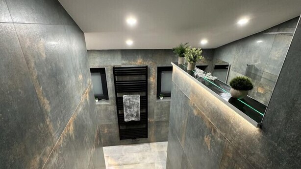 A modern staircase with grey tiles, recessed lighting, and a reception desk with plants. - Relaxen im Weindorf Mayschoß Fewo 3 (Mayschoß)