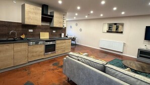 Een moderne keuken met inbouwapparatuur, een grijze bank en een flatscreen televisie.