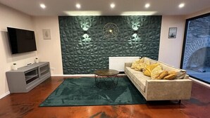Een moderne woonkamer met een flatscreen televisie, een bank, een salontafel en een unieke, structurele wand.