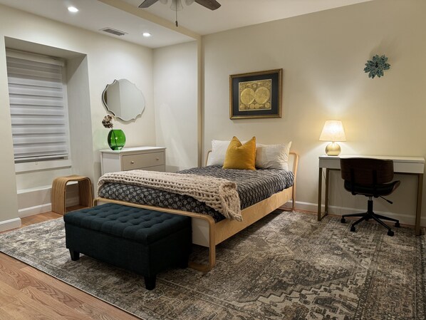 A bedroom with a bed, bedside table, lamp, chair, and a decorative mirror.
