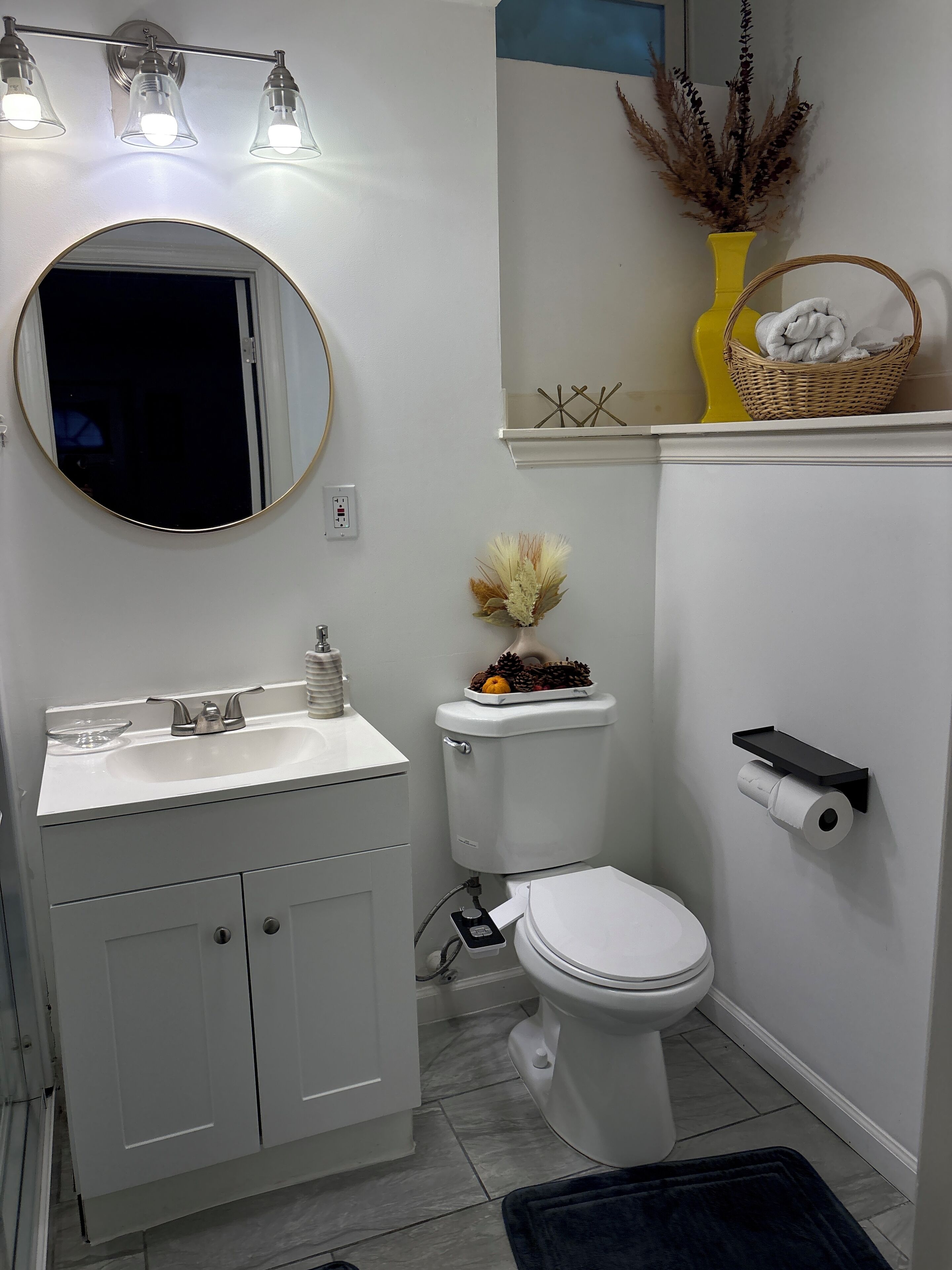 Ein Badezimmer mit weißem Waschbecken, Spiegel, Toilette und Ablagefläche mit Dekoration.