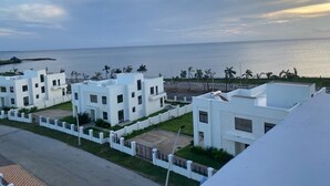 A coastal residential area with modern white buildings, a view of the sea, and a clear sky.