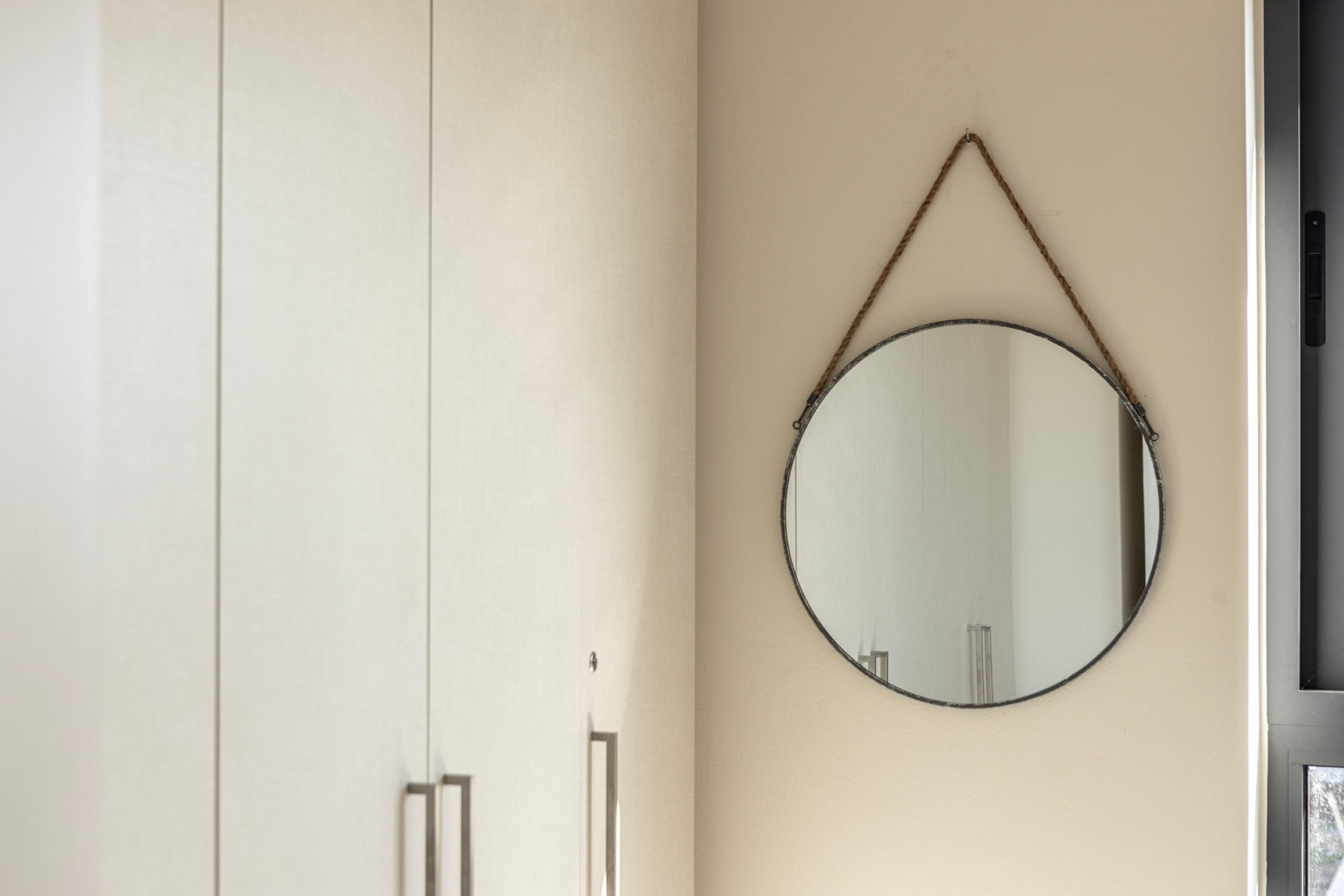 Una habitación con un espejo grande en la pared, un armario y una puerta.