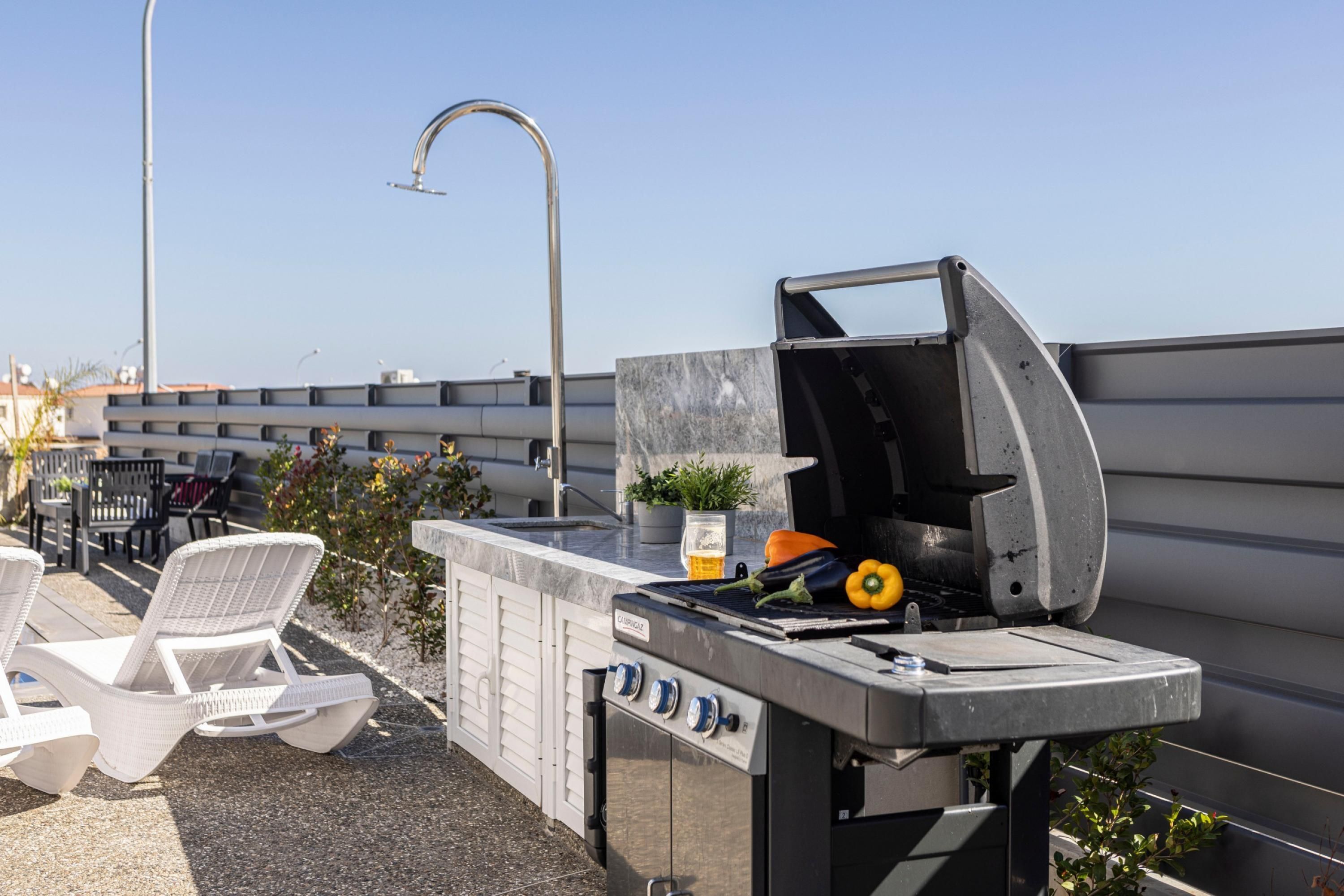 Una terraza en la azotea con una parrilla, asientos al aire libre y vistas del horizonte de la ciudad.