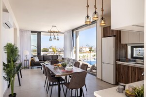 Una cocina moderna con una isla grande, un comedor con vistas a la piscina y una sala de estar con un sofá y una mesa de centro.