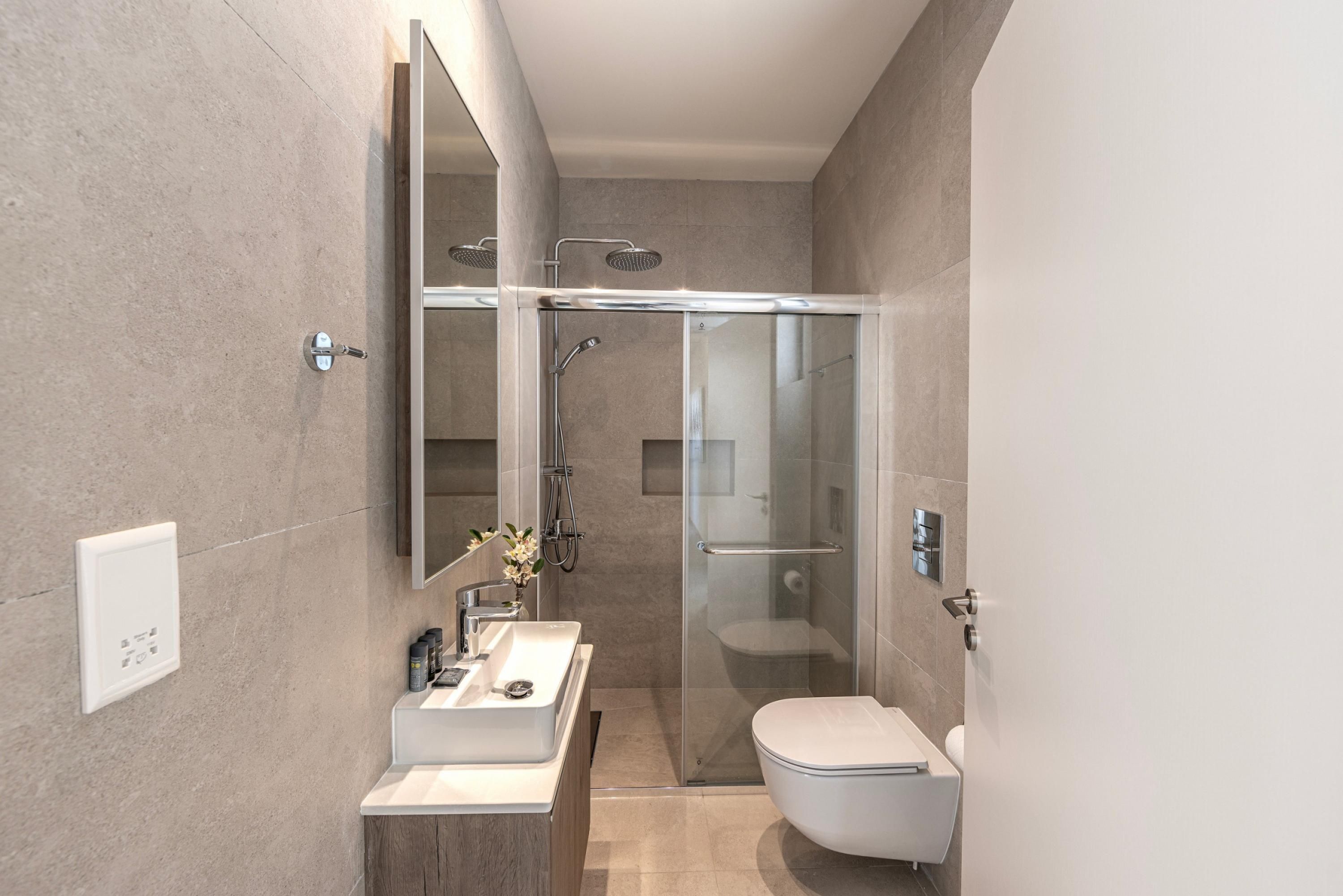 A modern bathroom with a glass-enclosed shower, a white sink, and a toilet.