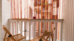 A balcony with two wooden chairs and a table, with colorful fabric draped across the railing. - 3 DOUBLE ROOMS IN THE CENTER OF ROME! (Roma)