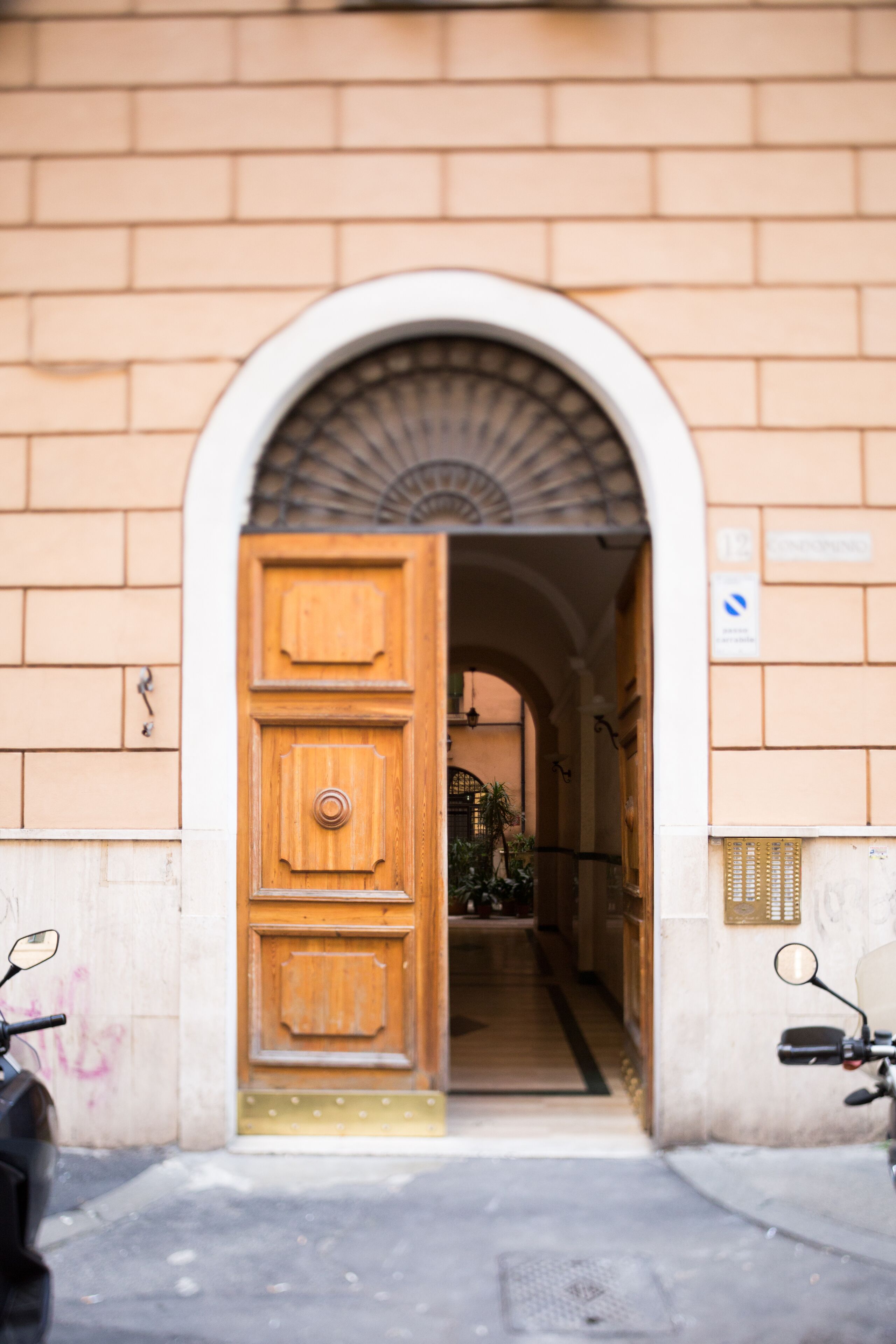 Un ingresso ad arco a un edificio con una porta in legno e un muro in mattoni.