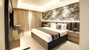 A modern bedroom with a large bed, bedside tables, a desk, and a mirror. - Stepstones Hotels and Inn (Gurugram)