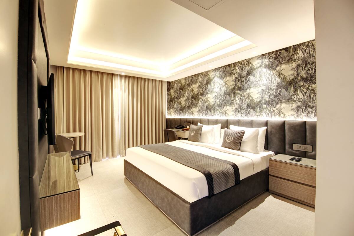 Une chambre moderne avec un grand lit, des tables de chevet, un bureau et un miroir.