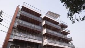 A multi-story building with balconies, a sign indicating a restaurant, and visible power lines. - Stepstones Hotels and Inn (Gurugram)
