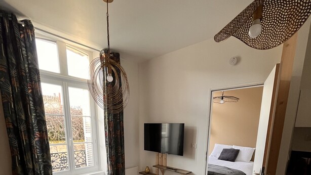 A modern living room with a wooden dining table, a sofa, and a TV mounted on the wall. - Appartement Douillet (Angoulême)