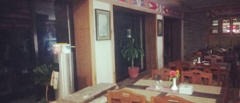Un interior de restaurante con mesas y sillas de madera, una planta en maceta y un adorno en la pared.