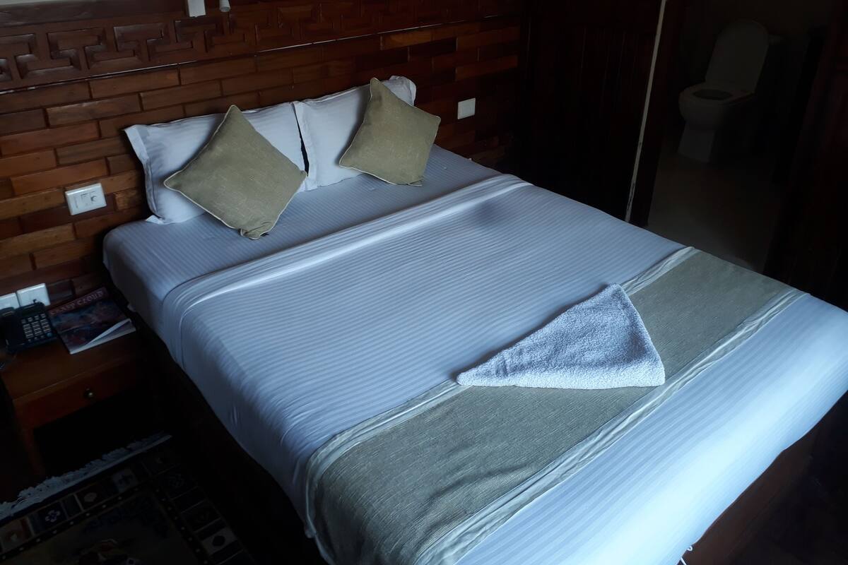 A neatly made bed with a wooden headboard, two pillows, and a blanket.