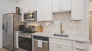 Een moderne keuken met roestvrijstalen apparatuur, witte kasten en een marmeren aanrecht.
