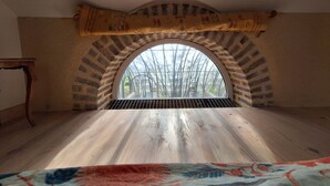A room with a wooden floor, a large arched window, and a patterned rug.