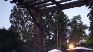 A hot tub with blue LED lights, surrounded by a pergola and outdoor seating.