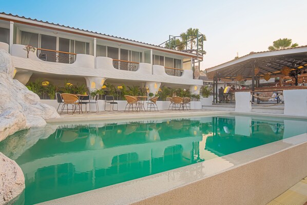 A pool area with lounge chairs and a covered seating area.