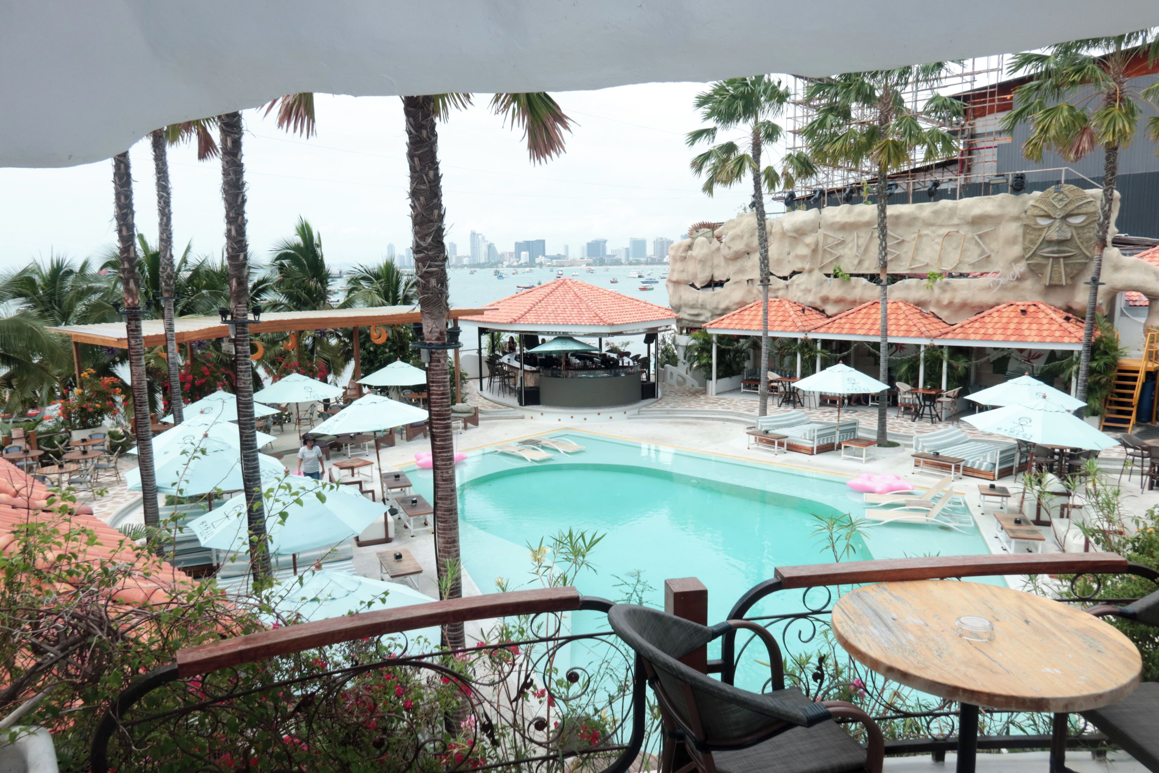 A resort pool area with lounge chairs, umbrellas, and a stage for events.