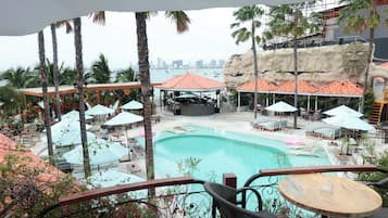 A resort pool area with lounge chairs, umbrellas, and a stage for events.