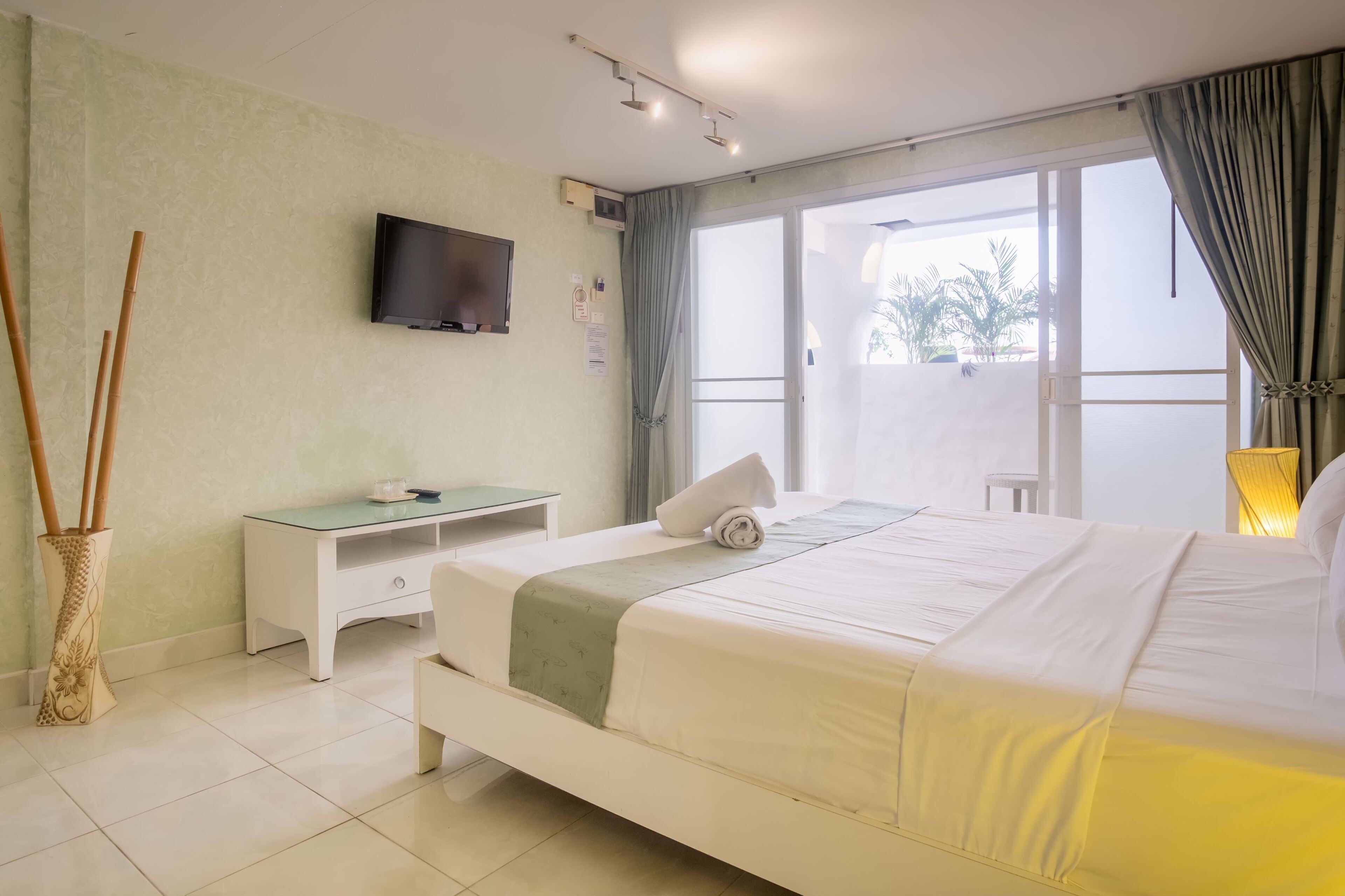 A hotel room with a bed, a desk, a television, and a large window.