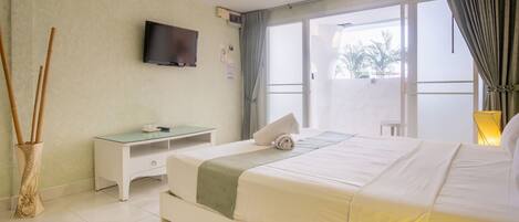 A hotel room with a bed, a desk, a television, and a large window.