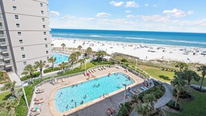 A hotel with a swimming pool, beach view, and a high-rise building.