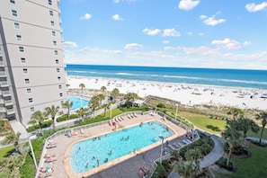 A hotel with a swimming pool, beach view, and a high-rise building.
