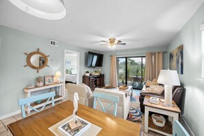 Un salon comprenant une table à manger, un canapé, un téléviseur et un ventilateur de plafond.