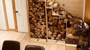 Ein Zimmer mit einer Holztreppe zu einem Schlafbereich, einem Kamin und einem Essbereich mit Stühlen.