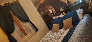 Ein Schlafzimmer mit einem geblümten Bettbezug, einem Nachttisch mit Lampe und einer Wanddekoration.