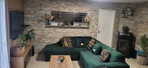 Ein Wohnzimmer mit einem grünen Sofa, einem Holztisch, einem Fernseher und einem Kamin.