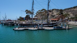 Un port où plusieurs bateaux sont amarrés à un quai, entouré de bâtiments et d’un paysage vallonné.