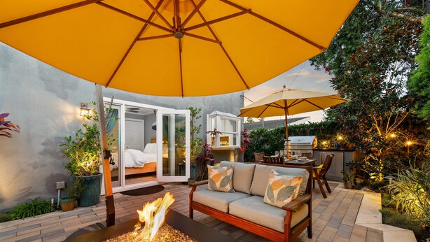 Un espace patio doté d’un foyer extérieur, de sièges et de parasols pour créer de l’ombre.