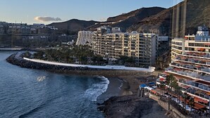 Un hotel sulla costa con diversi piani, una passeggiata lungomare e un litorale roccioso.
